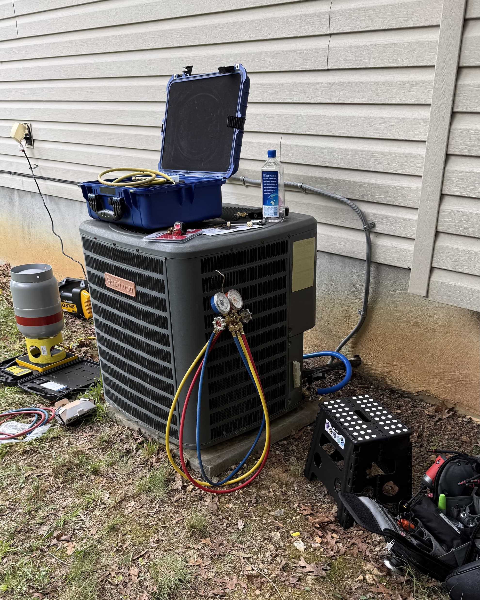 Manifold gauges connected to an outdoor AC condenser to verify refrigerant charge during a repair diagnostic
