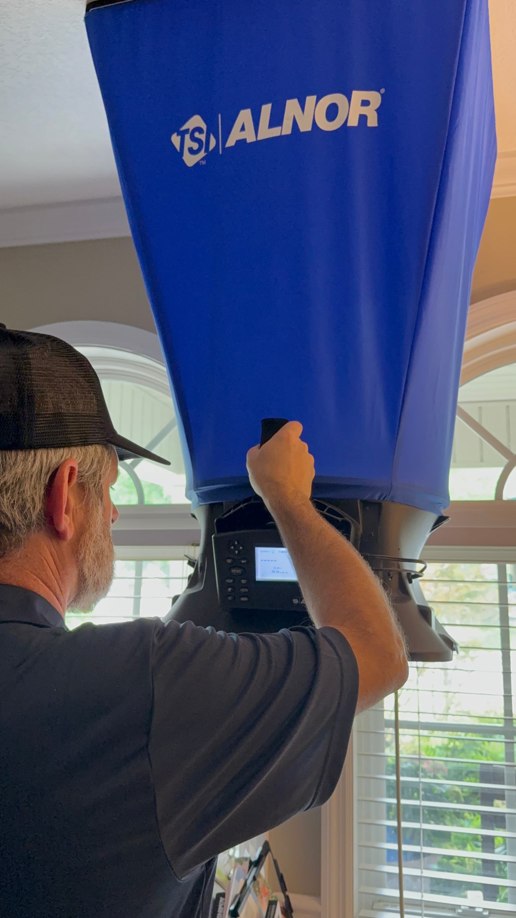 Measuring supply airflow at a register with an ALNOR balometer capture hood during a duct assessment