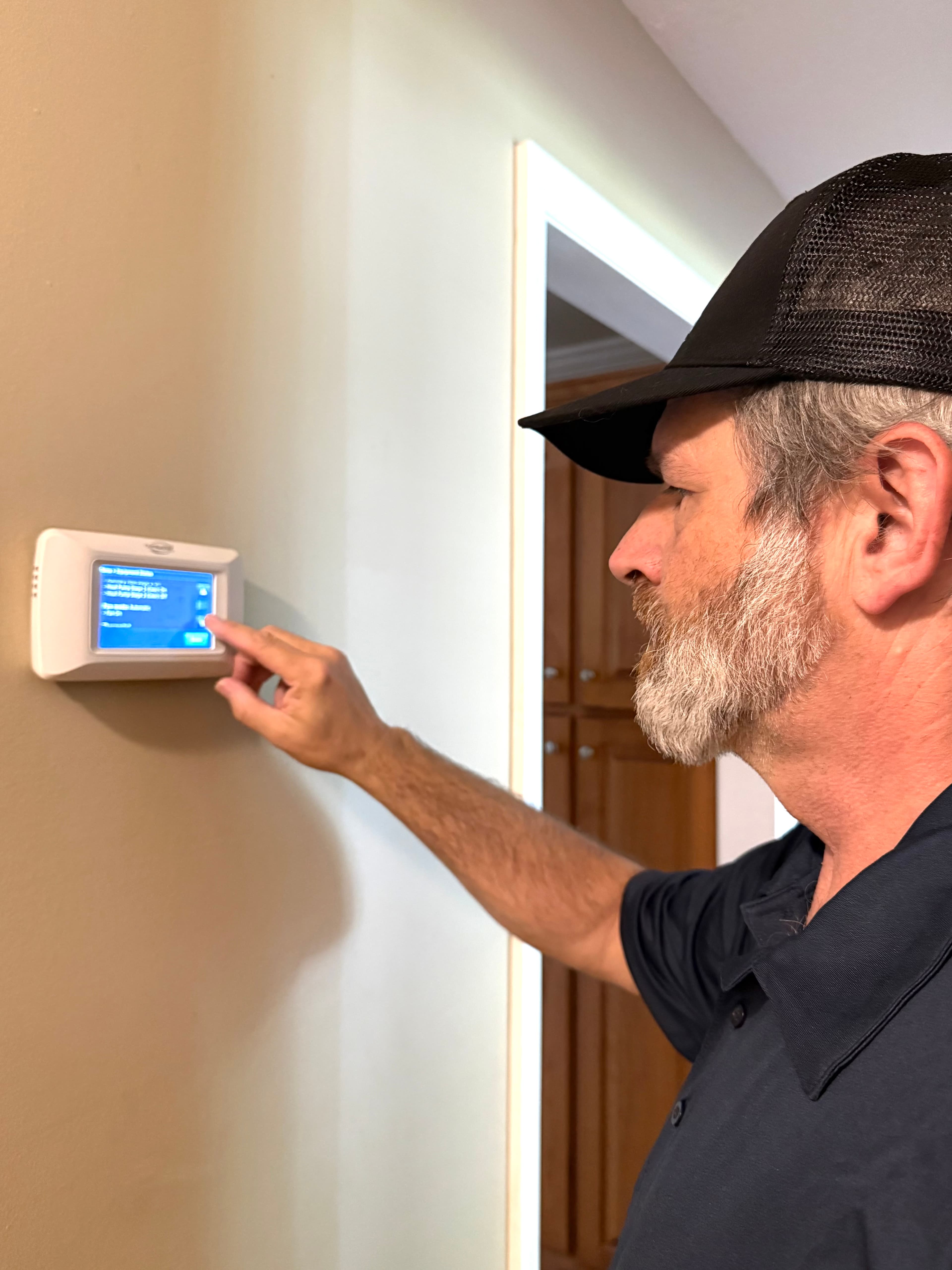 Russell Joplin, owner, checking a smart thermostat during a diagnostic visit